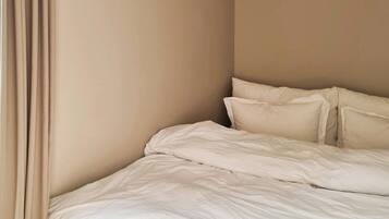 A bedroom with a bed, curtains, and a ceiling light fixture.
