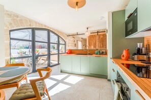 Eine moderne Küche mit einem großen Fenster, einem Essbereich mit Tisch und Stühlen sowie Blick ins Freie.