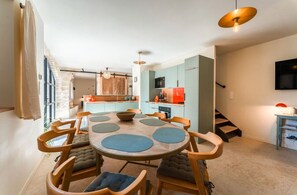 Eine moderne Küche mit Essbereich, ausgestattet mit einem runden Tisch, blauen Tischsets und Holzstühlen.