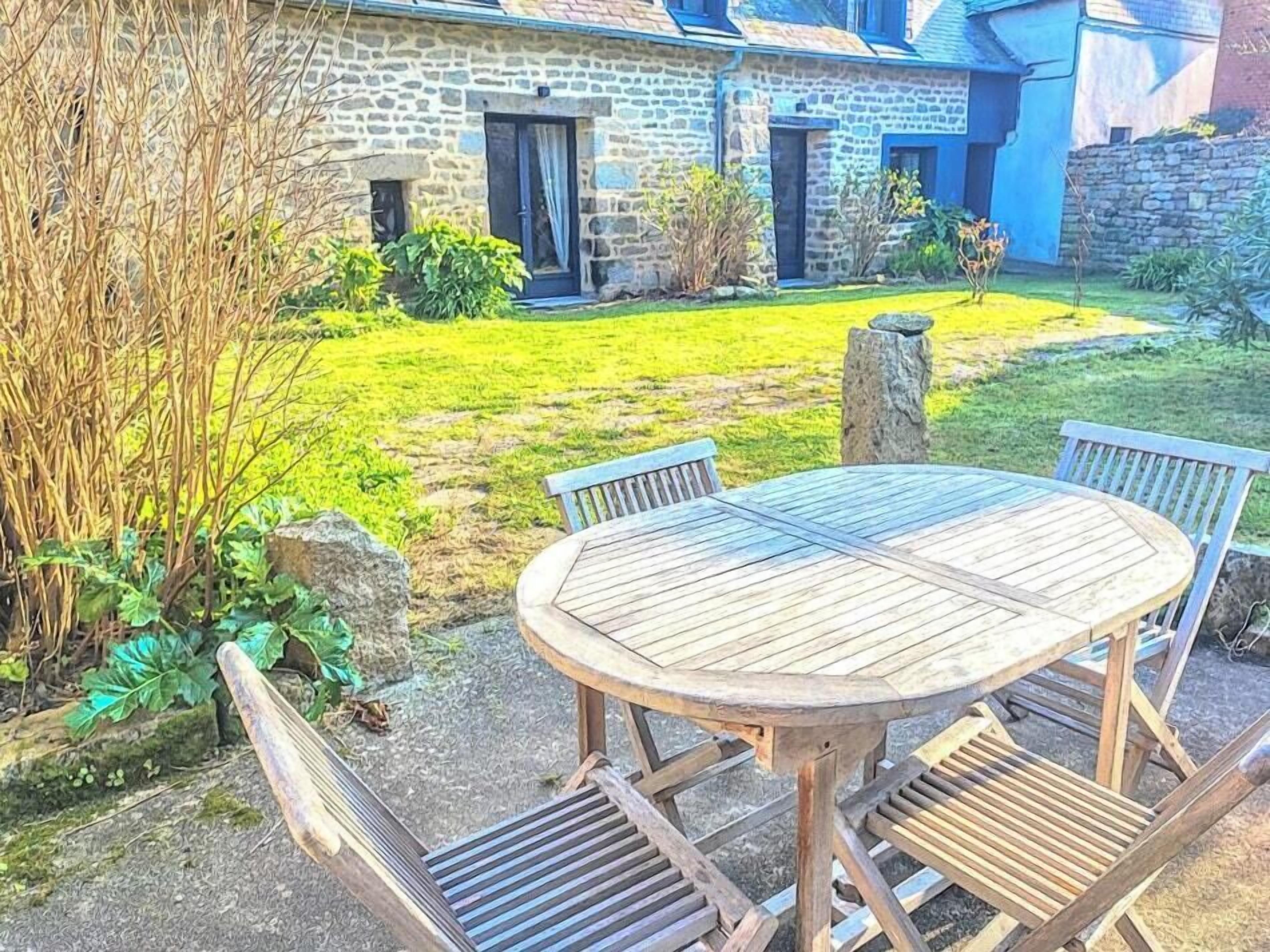 A stone house with a wooden table and chairs in the yard.