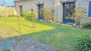 Ein Haus aus Stein mit einem geneigten Dach, zahlreichen Fenstern und einem gepflegten Rasen.