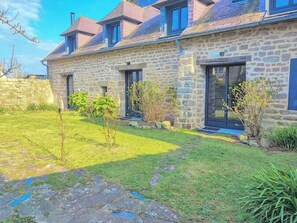 A stone house with a sloped roof, multiple windows, and a well-maintained lawn. - Fisherman's house 40m from ocean in Kerity (Penmarch)