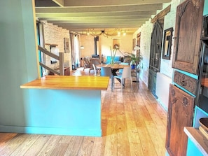 A spacious room with a wooden floor, a central seating area with chairs and a table, and a staircase leading to an upper level. - Fisherman's house 40m from ocean in Kerity (Penmarch)