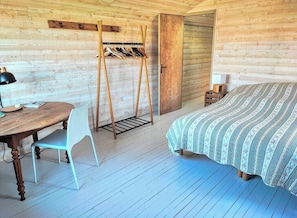 A wooden cabin room with a bed, a table with a chair, and a coat rack. - Fisherman's house 40m from ocean in Kerity (Penmarch)