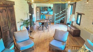 Ein gemütliches Interieur mit Holzboden, einem Essbereich mit Tisch und Stühlen sowie einer Treppe zu einer oberen Ebene.
