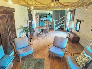 A cozy interior with wooden flooring, a dining area with a table and chairs, and a staircase leading to an upper level. - Fisherman's house 40m from ocean in Kerity (Penmarch)