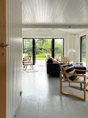 A modern interior with a sofa, armchair, and a dining area with a table and chairs. - Home embraced by green nature in Højby (Højby)