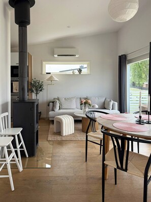 Ein modernes Wohnzimmer mit einer Couch, einem Couchtisch, Stühlen, einem Kamin und einem großen Fenster.