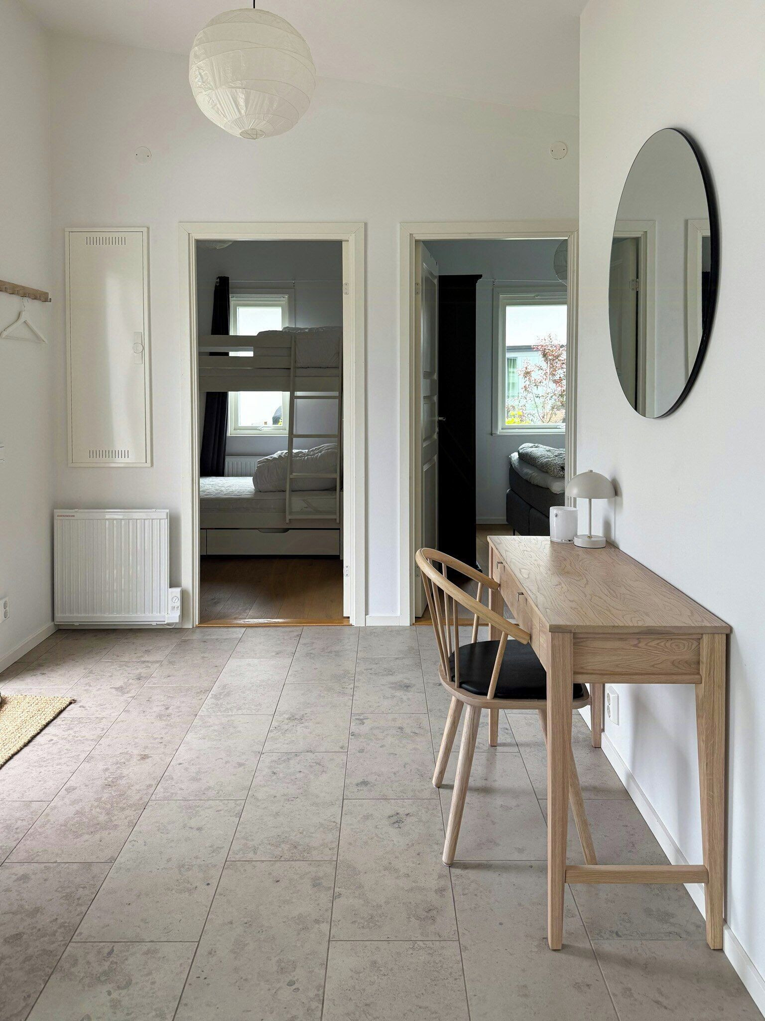 A room with a wooden table, a chair, a radiator, and a hanging light fixture.
