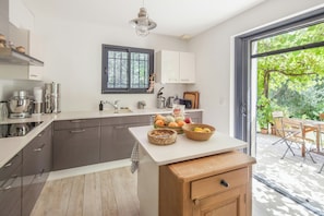 Eine moderne Küche mit einem großen Fenster, einem Essbereich mit Tisch und Stühlen und Blick auf einen Garten.