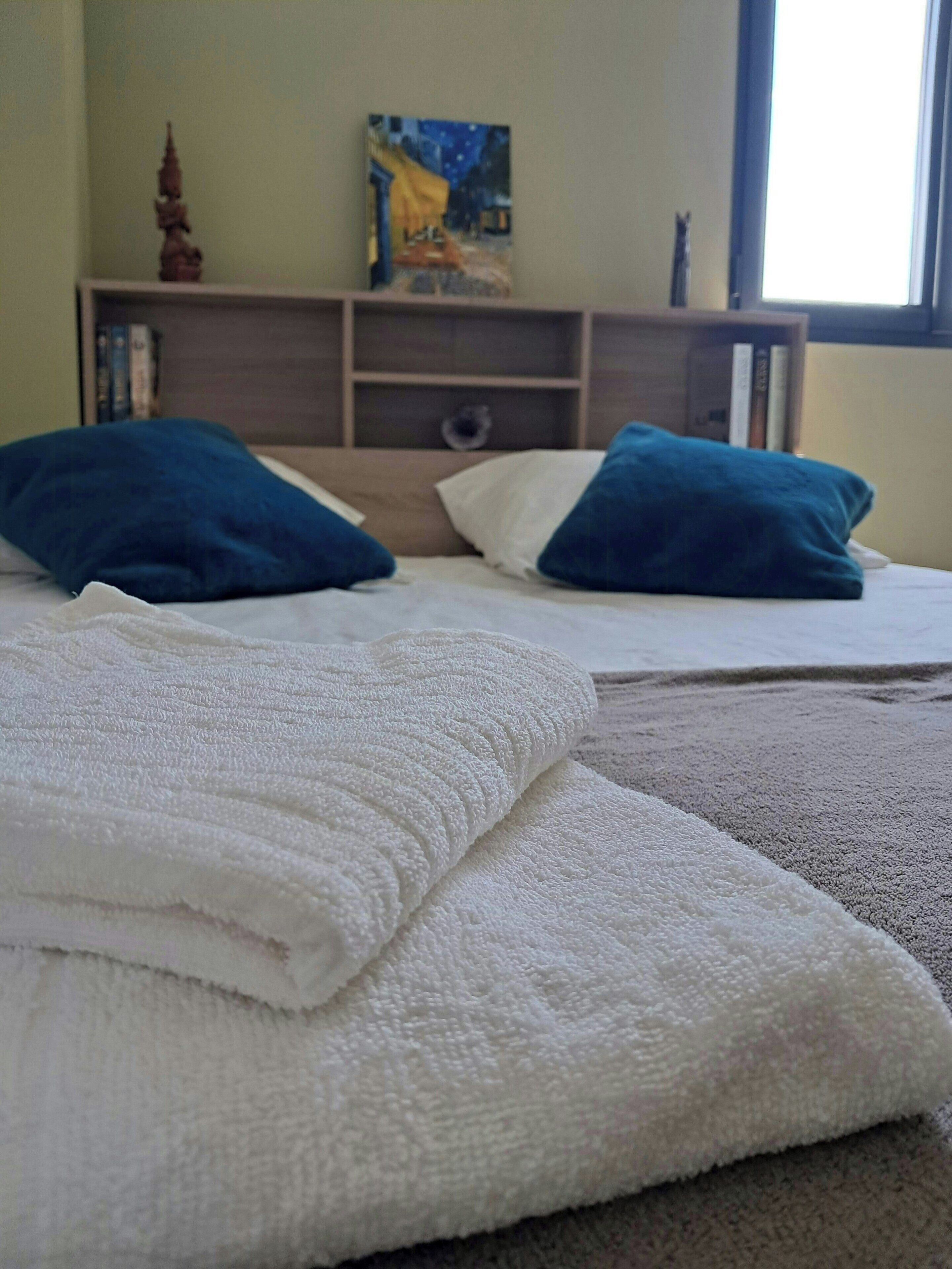 Een hotelkamer met twee bedden, een schilderij aan de muur en een raam.