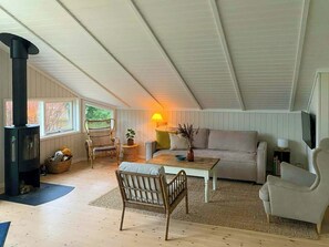 Ein gemütliches Zimmer mit Kamin, einer Couch, einem Couchtisch und Korbstühlen.