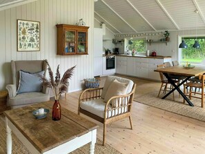 Ein gemütliches Wohnzimmer mit einer Couch, einem Esstisch und einem Korbstuhl.
