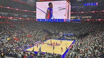 A basketball game at the Little Caesars Arena with a large crowd.
