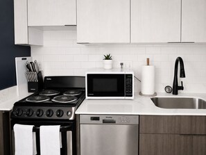 A modern kitchen with a stove, microwave, dishwasher, and stainless steel sink.