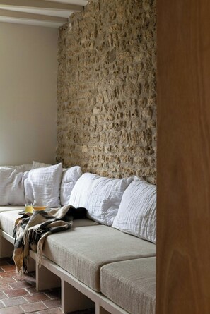 Ein Zimmer mit einer Steinswand, einem weißen Sofa mit Kissen und einer Holztür.