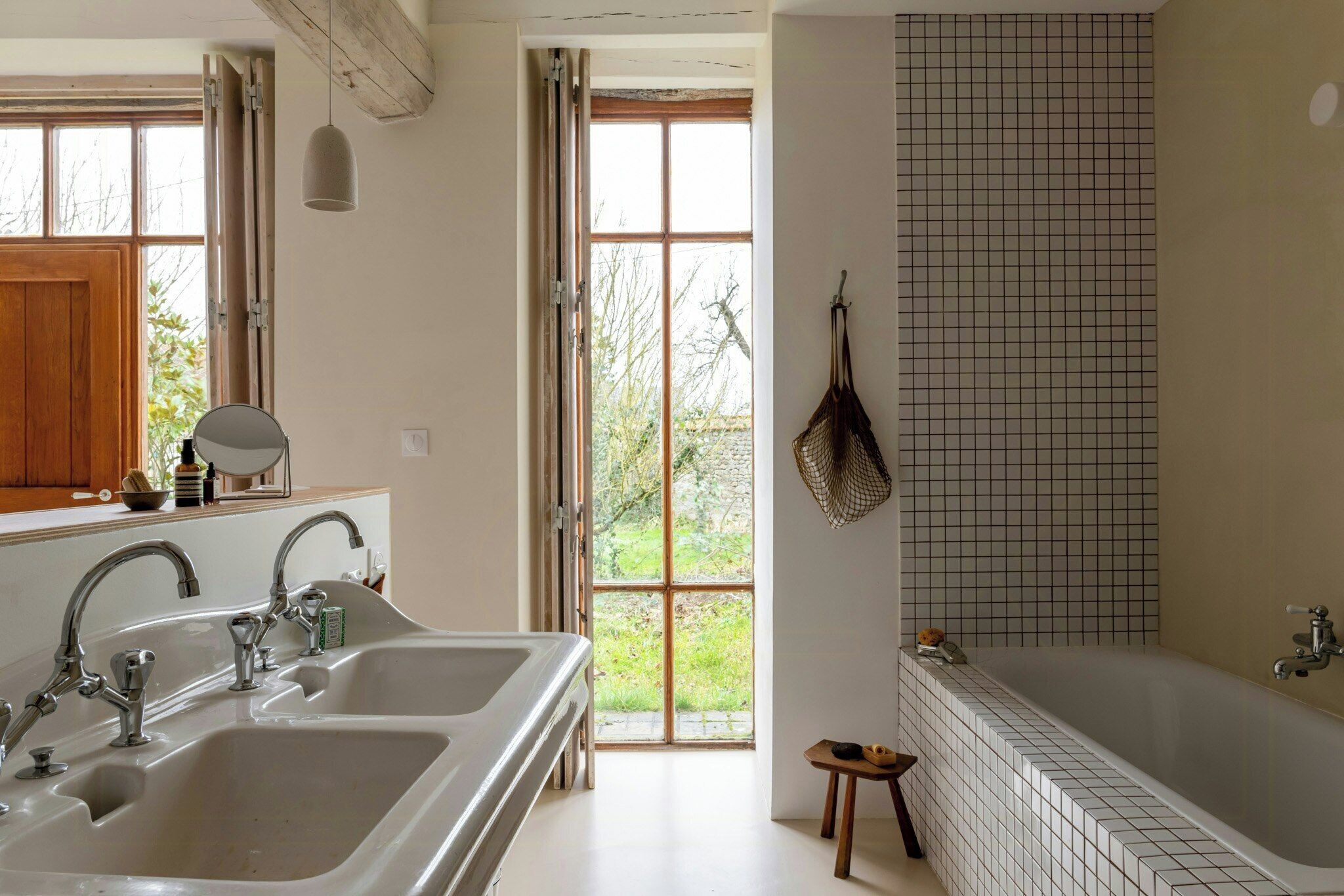 Un baño con bañera, lavamanos y ventana con vistas a zonas verdes.
