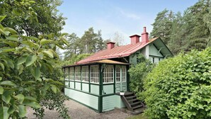Ein grünes Holzhaus mit rotem Dach, umgeben von üppiger Vegetation.