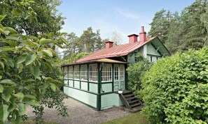 Ein grünes Holzhaus mit rotem Dach, umgeben von üppiger Vegetation.