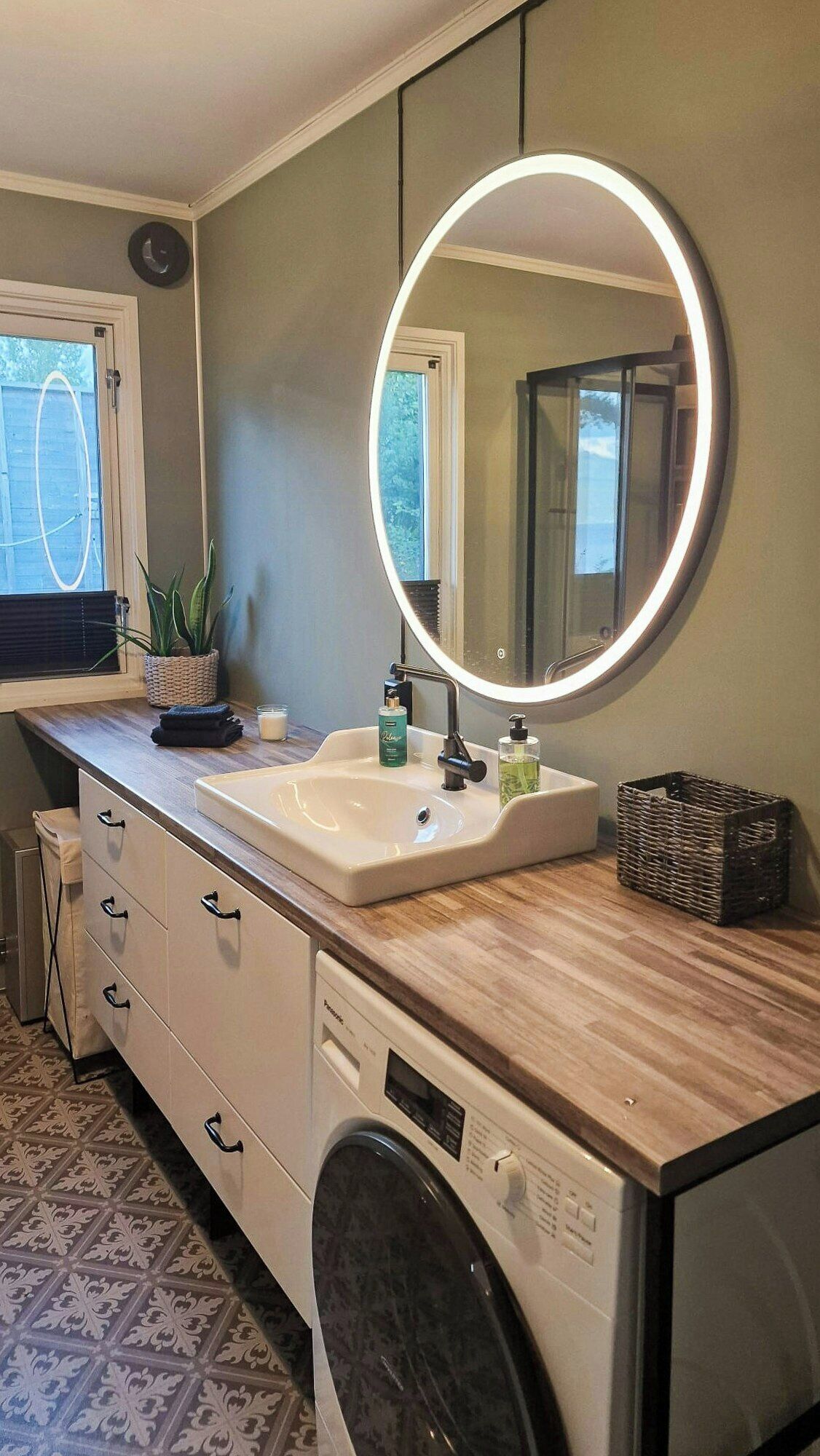 Une salle de bain avec un lavabo, un miroir et un lave-linge.
