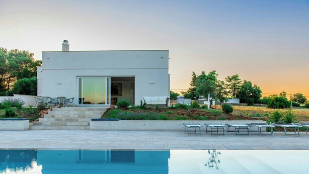 Una casa moderna con piscina, area relax esterna e giardino.