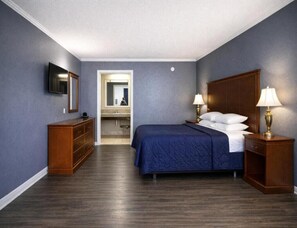 A hotel room with a bed, bedside lamps, a dresser, a TV, and a mirror. - Comfort Room, one king bed accessible non-smoking (Antioch)