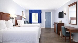 A hotel room with two beds, a desk, a chair, a television, and a door.
