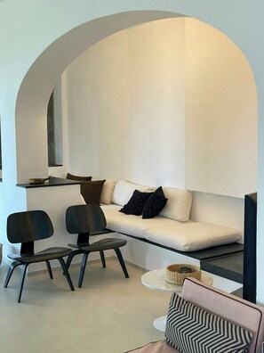 A modern living room with a sofa, two chairs, a small round table, and a television.
