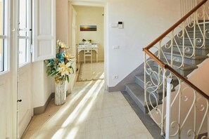 Ein Flur mit Treppe, einer weißen Tür und einer dekorativen Vase mit Blumen.