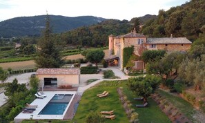 Una villa con piscina, mobiliario de exterior y jardín.