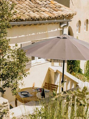 Eine Terrasse mit Tisch, Stühlen und Sonnenschirm.