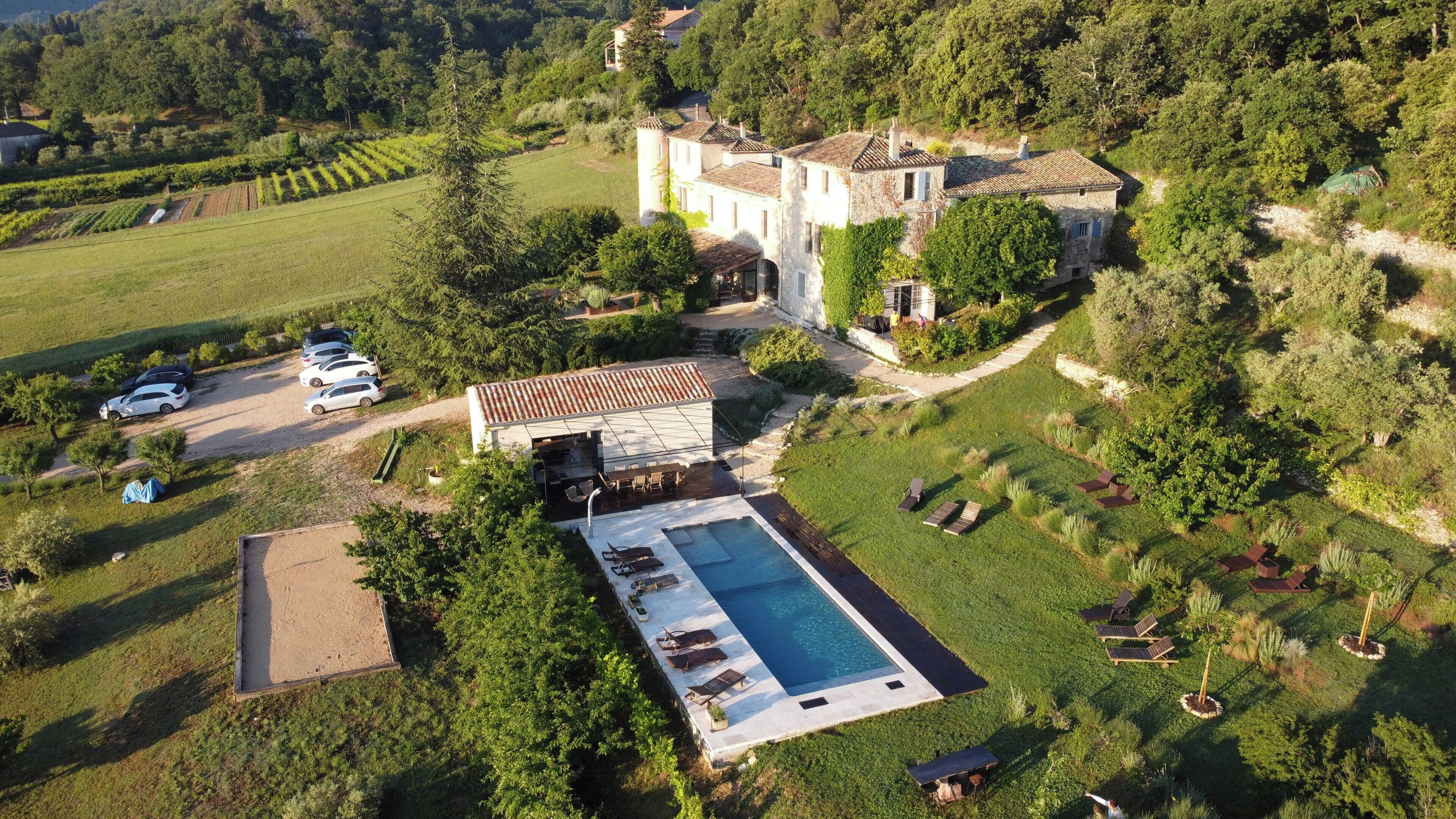 A large estate with a swimming pool, multiple buildings, and surrounding greenery.