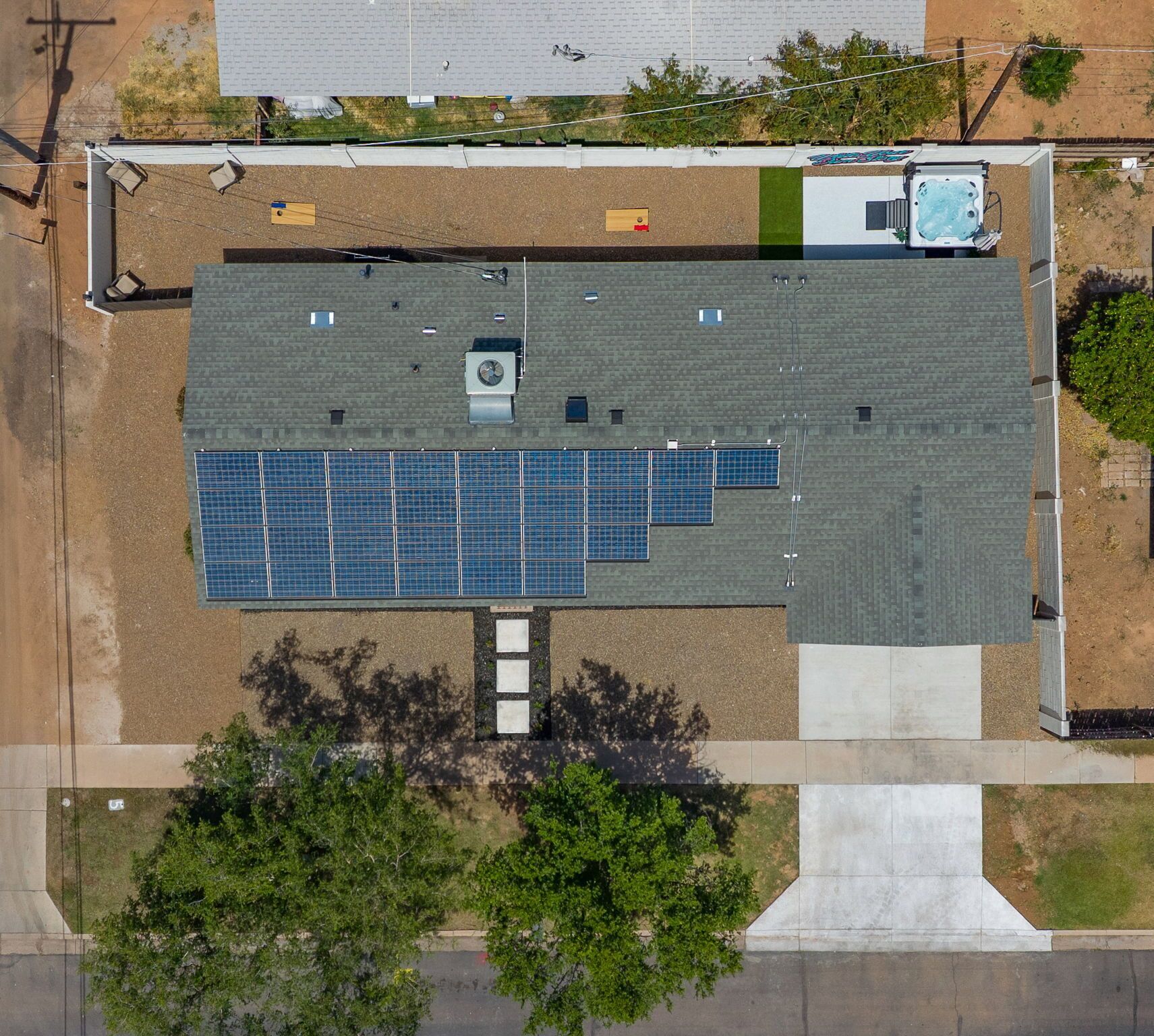 A rooftop with solar panels, a hot tub, and a small building with a window.