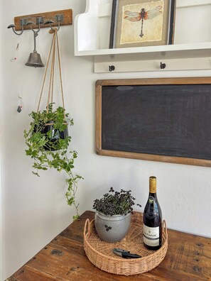 A wooden table with a bottle of wine, a potted plant, and a chalkboard on a white wall. - Front row holiday home with sunset on Odden (Yderby lyng Sjællands odde)