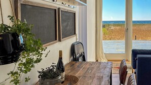Uma área de refeições com mesa de madeira, cesta de vime e plantas em vasos.
