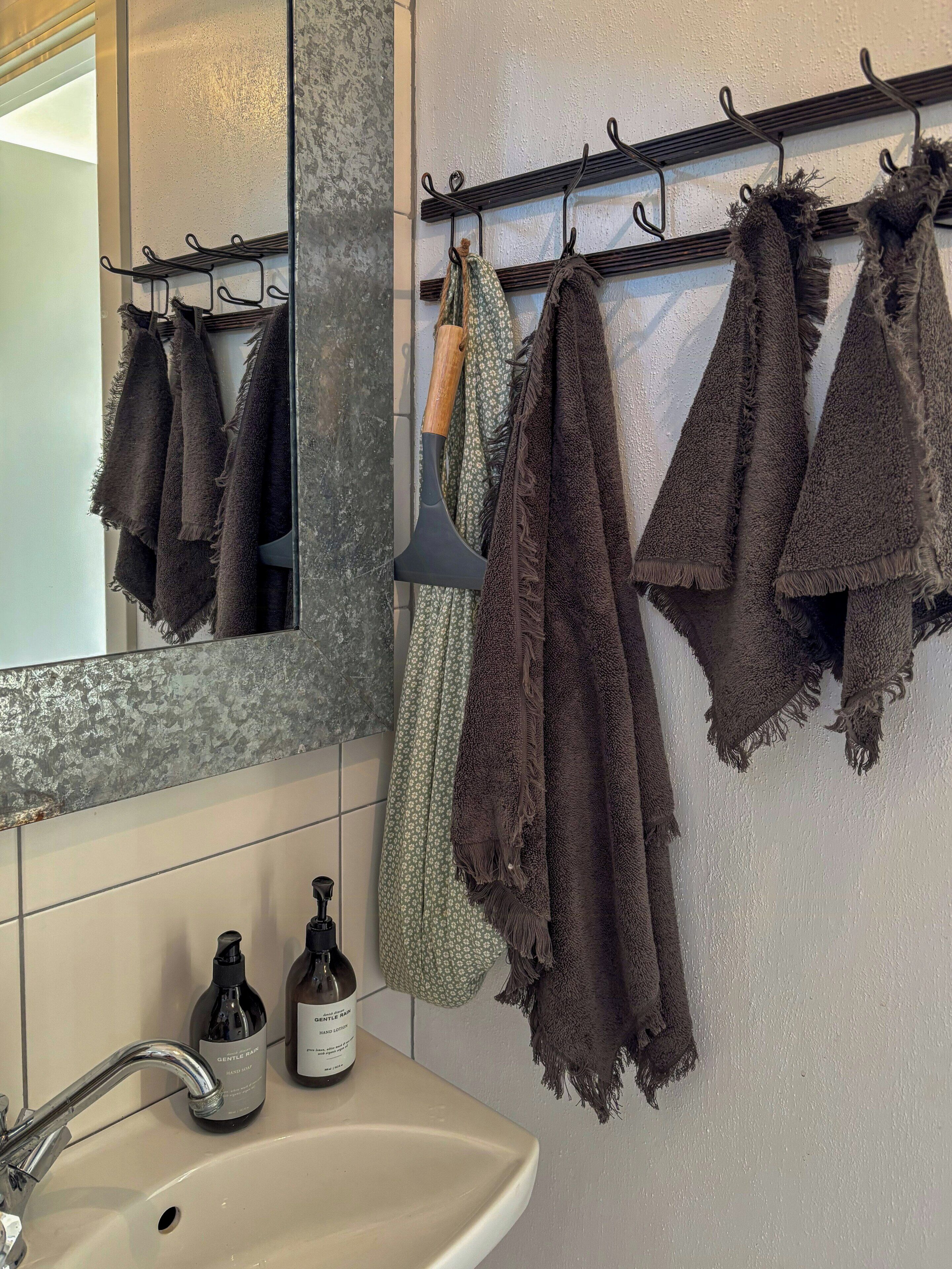 Une salle de bain équipée d’un lavabo, de deux flacons de lotion pour les mains, d’un miroir et d’un porte-serviettes avec plusieurs serviettes.