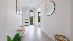 Ein Korridor mit Holzboden, einem runden Spiegel und zwei Hocker.