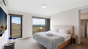 Ein Schlafzimmer mit einem großen Bett, Blick auf die Landschaft und einem Fenster.