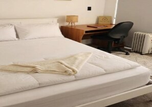 Habitación de hotel con cama, escritorio, silla y radiador.