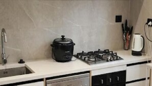 A kitchen with a gas stove, a black slow cooker, a coffee maker, and a sink. - Stylish Wesley Retreat (Auckland)