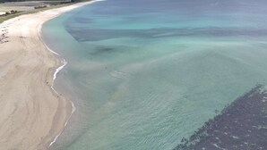 An aerial view of a beach with clear water, sandy shore, and distant vegetation. - Bénodet, charming stone house with beautiful garden (BENODET)