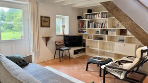 A living room with a sofa, a TV, a bookshelf, and a staircase. - Bénodet, charming stone house with beautiful garden (BENODET)