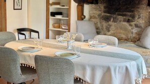 A dining area with a round table set for four, surrounded by grey upholstered chairs. - Bénodet, charming stone house with beautiful garden (BENODET)