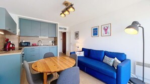 A compact living space with a kitchen, dining area, and a blue sofa. - QUIBERON - 2 rooms - 33m2 - City center (QUIBERON)