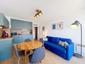 A compact living space with a kitchen, dining area, and a blue sofa. - QUIBERON - 2 rooms - 33m2 - City center (QUIBERON)