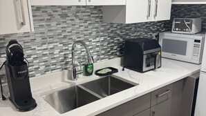 A modern kitchen with a double sink, a coffee maker, a toaster, and a microwave. - Serene and Stylish House Rental in Brighton, Saskatoon (Saskatoon)
