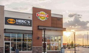 A Family Pizza store with a visible address number 137, adjacent to a Hercules Nutrition store. - Serene and Stylish House Rental in Brighton, Saskatoon (Saskatoon)