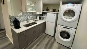 A compact kitchen with a built-in washer and dryer, a sink, a microwave, and cabinets. - Serene and Stylish House Rental in Brighton, Saskatoon (Saskatoon)