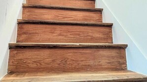 A wooden staircase with a white handrail and a door at the top.