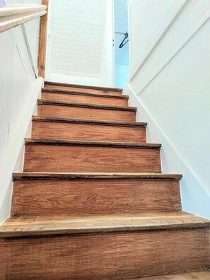 Un escalier en bois avec une rampe blanche et une porte en haut.
